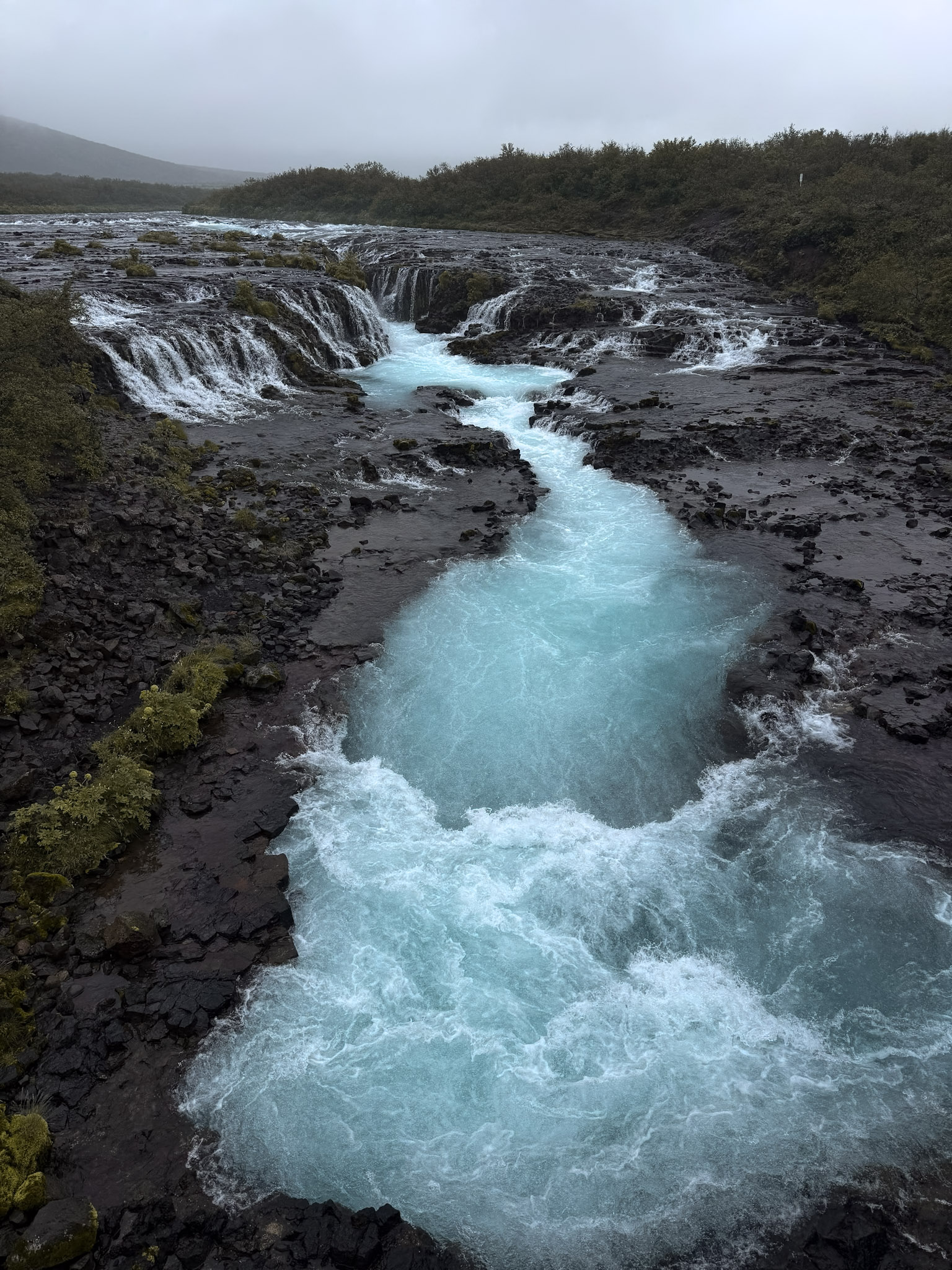 Blue waterfall flowing through black sand banks